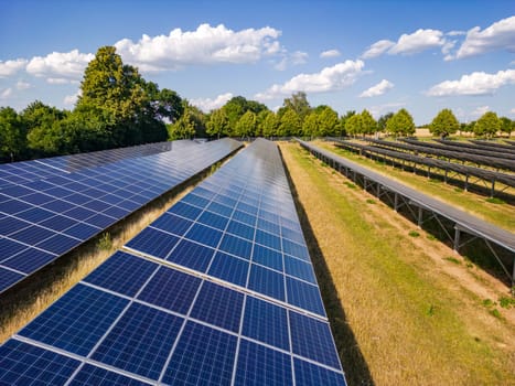 Solar panels of an open space installation with photovoltaic modules on an agricultural field on a day with sunshine, drone perspective, Germany