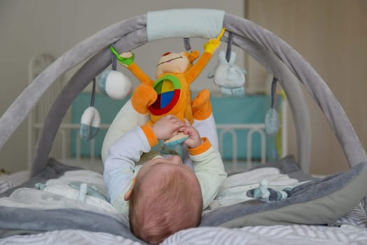 Baby boy playing with hanging toys on a developing mat
