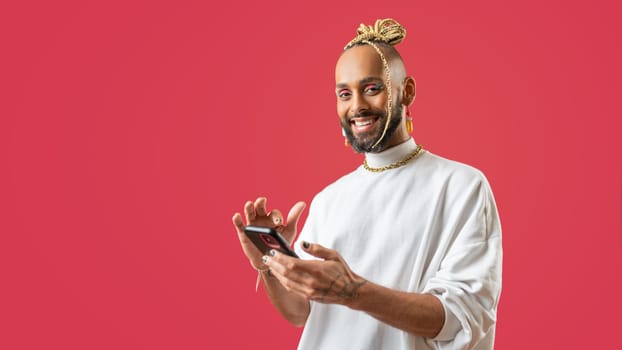 Trendy black latin gay man in white clothes use smartphone looking at camera on pink background studio portrait People lifestyle fashion lgbtq concept