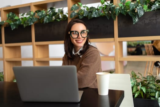 Woman Wearing Glasses using Laptop. Smiling businesswoman in eyeglasses and casual clothes working with laptop computer watching side. Elegant business female medium shoot
