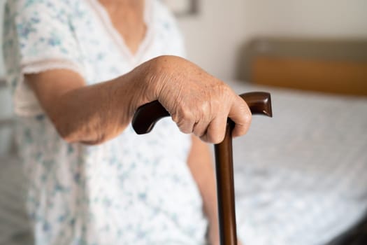 Asian elderly disability woman holding waling stick, wood cane, round handle, walking aid for help to walk.