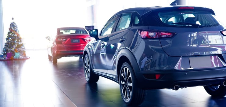 Rearview of car parked in luxury showroom. Car dealership office. New car parked in modern showroom. Car for sale business concept. Automobile leasing and insurance agent concept. Electric vevicle.                 