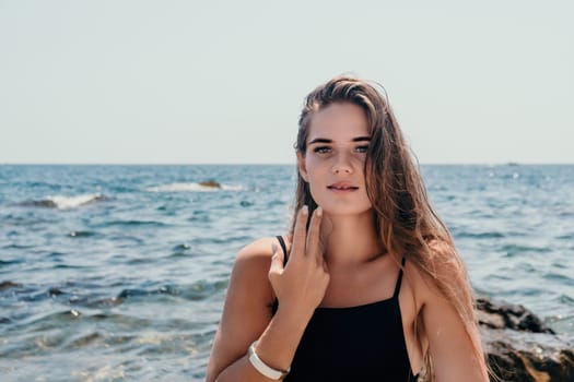 Woman travel sea. Young Happy woman in a long red dress posing on a beach near the sea on background of volcanic rocks, like in Iceland, sharing travel adventure journey