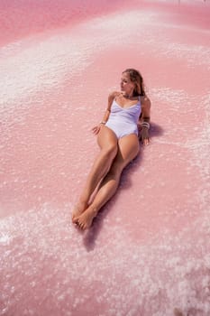 Woman pink salt lake. She lies in a white bathing suit. Wanderlust photo for memory.