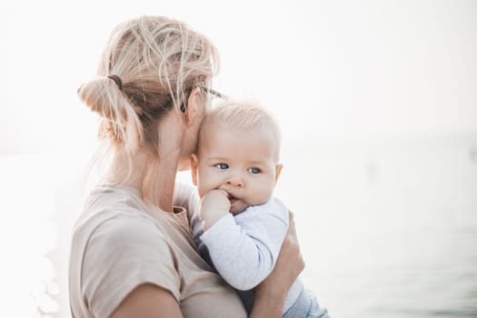 Tender woman caressing her little baby boy infant child outdoors. Mother's unconditional love for her child.