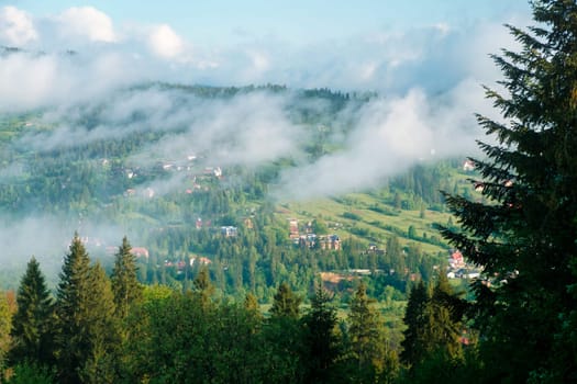 Aerial view village in mountain valley in fog. Morning fog on a hills of mountain village. Beautiful idyllic landscape. Carpathians, Ukraine, Europe. download photo