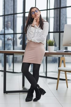 business woman standing in full length and looking at the camera with her hands crossed in the office