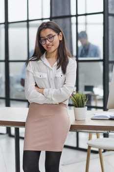 business woman standing in full length and looking at the camera with her hands crossed in the office