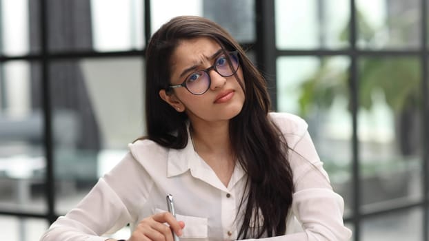 Photo of beautiful woman looking at camera while sitting at office