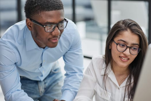 happy Middle Eastern and African American partners using laptop computer at table desktop