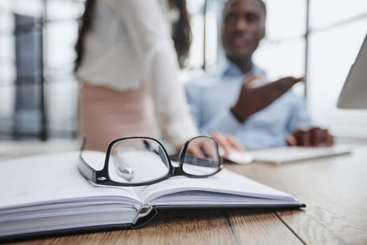 The glasses are on the work table. Against a blurred background, the guy works at a laptop