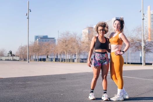 two multiethnic sport friends smiling happy looking at camera standing on the city, concept of friendship and sportive lifestyle, copy space for text