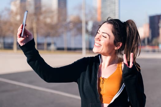 beautiful sportswoman smiling happy taking a selfie with mobile phone in the street, concept of social media and sportive lifestyle
