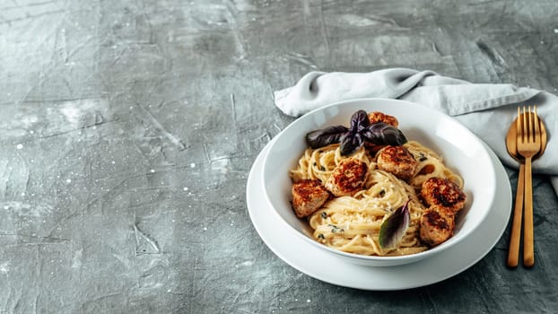 Meatballs Pasta Carbonara in white plate over gray background. Close up view of creamy carbonara pasta with meatballs with copy space left. Comfort food concept