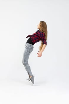 The silhouette of the girl seen in profile. The girl poses for the photo and performs a difficult acrobatics by standing on tiptoe and arching her back. The girl is wearing fitted jeans, a checked shirt and sports shoes.