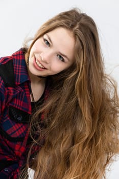 Close-up on the silhouette of a girl visible against a white background. The girl is smiling slightly and has a little crooked head. She has her hair pulled to the side. Her hair is very long, lush, healthy and shiny.