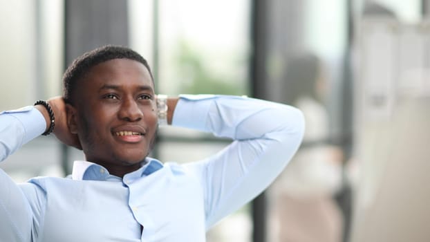 Job satisfaction. Cheerful businessman in formalwear holding head in hands while sitting at his desk in the office
