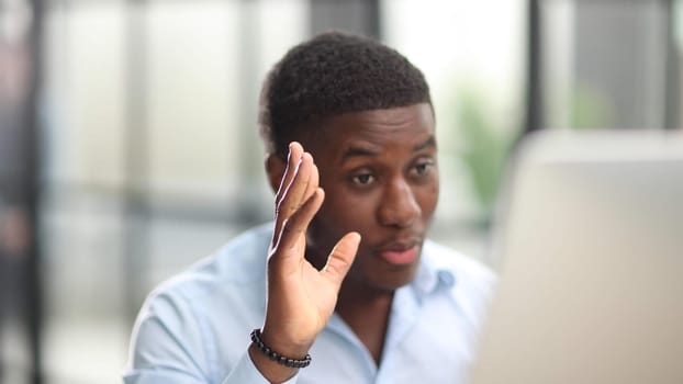 African American, middle aged man entrepreneur greets a client over a laptop