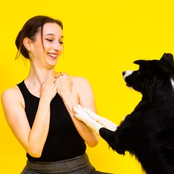 Excited girl dancing with border collie. Studio portrait lady looking at a dog with surprised smile.