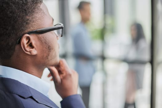 a black guy stands with his back and looks at his colleagues in the office