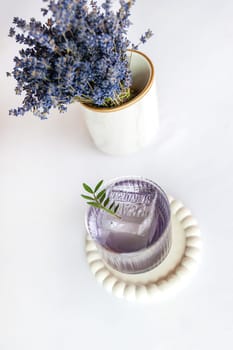 Lavender summer cocktail with ice in glass on the white table