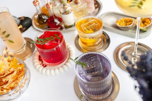 Five colorful summer cocktails in glasses on white table. Assortment of fresh summer drinks. Orange and red sangria cocktails, orange punch cocktail, margarita cocktail, tropical mule.