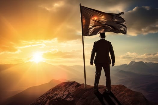 An inspiring image of a man standing atop a mountain peak, proudly holding a flag as a symbol of accomplishment.