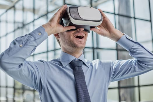 young man testing VR glasses or goggles sitting in the office room