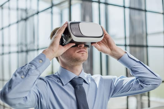 young man testing VR glasses or goggles sitting in the office room