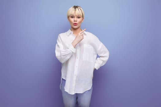 surprised fashionable woman with a bob haircut dressed in a white shirt points her finger to the side.