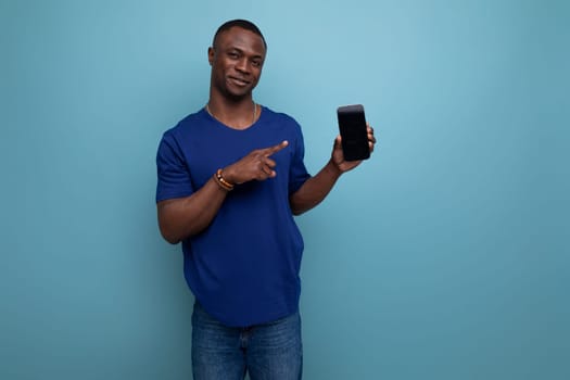 handsome young american man in blue t-shirt showing smartphone screen with mockup.