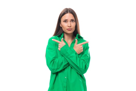 young european female model with well-groomed black hair and make-up dressed in a green shirt crossed her arms in front of her on a white background with copy space.