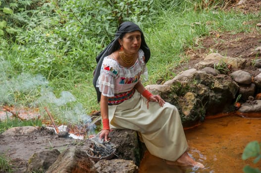 shaman woman preparing a bowl with herbs, sticks and fire for an ancestral rite from ecuador. High quality photo