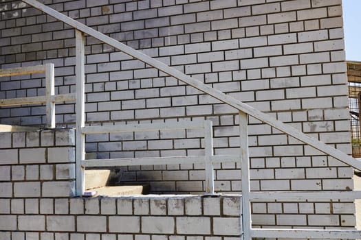 Photo of white brick wall and stairs. Climbing stairs. House. Construction and repair.