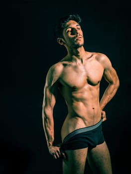 Muscular man pulling down underwear to show his butt, in studio shot