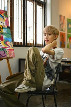 Art, education, creativity and people concept. Asian student man painting on canvas with watercolors at art class.