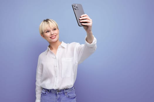 portrait of a young blond business woman with a short haircut in a white shirt taking a selfie on the background with copy space.