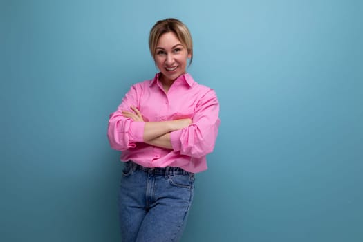 young smiling european blond office worker woman dressed in a pink shirt and jeans.
