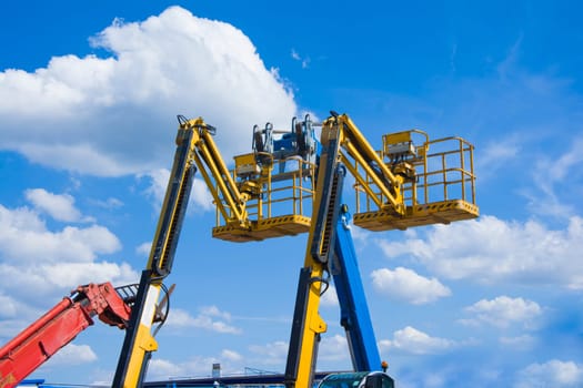 Lift buckets boom in the blue sky with clouds