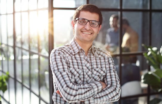 Young businessman with arms crossed standing in office lobby. success concept