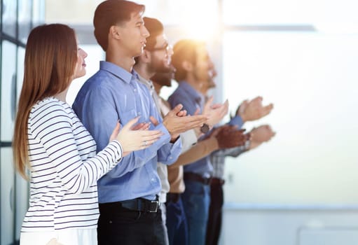 Applause. Group of cheerful young multi-ethnic people standing in a row and applauding to someone while standing