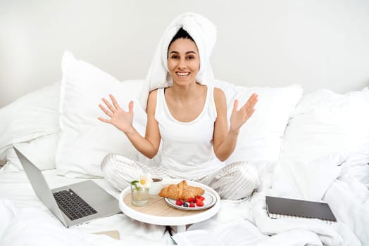 Happy young woman of Spanish appearance and received a surprise in the form of breakfast in bed. The girl raised her hands up in surprise and happiness. The best start to the work day.