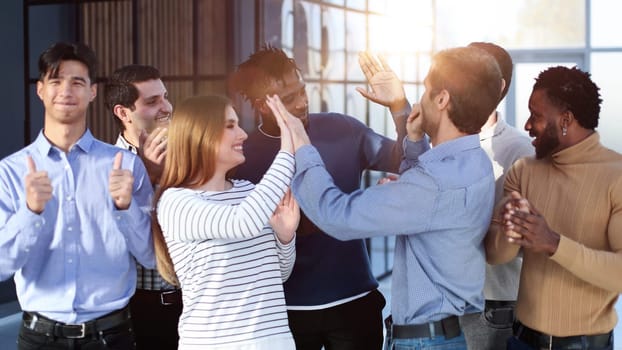 happy excited millennial employees shouting for joy, raising hands for emotional high fives.