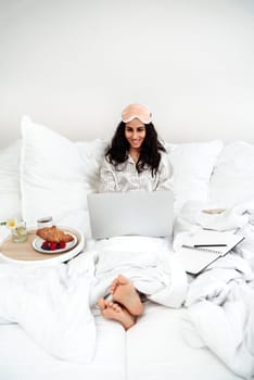 A young beautiful lady has just woken up in a hotel because of breakfast, she is looking through mail and actively texting. A woman starts her working day in the comfort and coziness of a hotel room