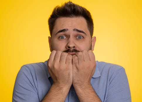 Stressed depressed caucasian man terrified about danger problems, suffering phobia, anxiety disorder, expresses fear, waving no, insecure, stress, panic. Young guy isolated on yellow studio background
