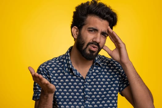Bearded indian man feeling hopelessness loneliness, nervous breakdown, loses becoming surprised by lottery results, bad fortune loss, unlucky news. Hindu young guy isolated on studio yellow background