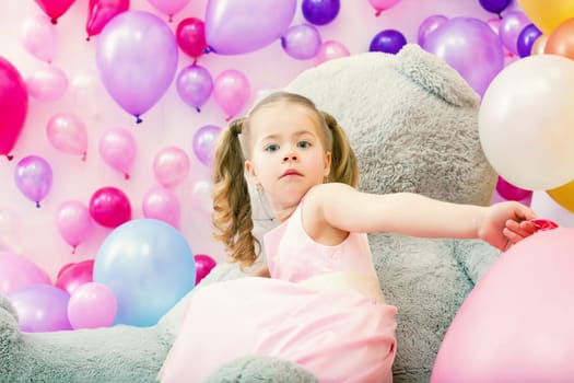Surprised girl posing at camera with pink balloons