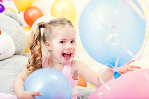 Portrait of cheerful little girl posing with blue balloons