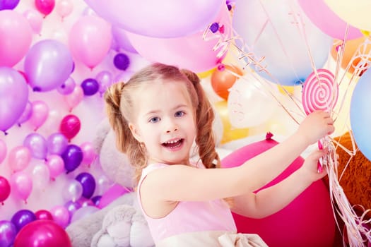 Merry little girl posing with bunch of colorful balloons