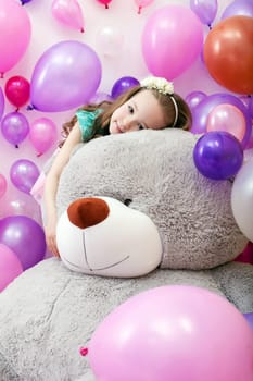 Image of cute curly girl posing lying on big plush bear